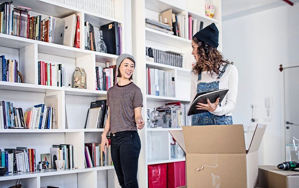 Lesbian couple standing in front of a bookshelf