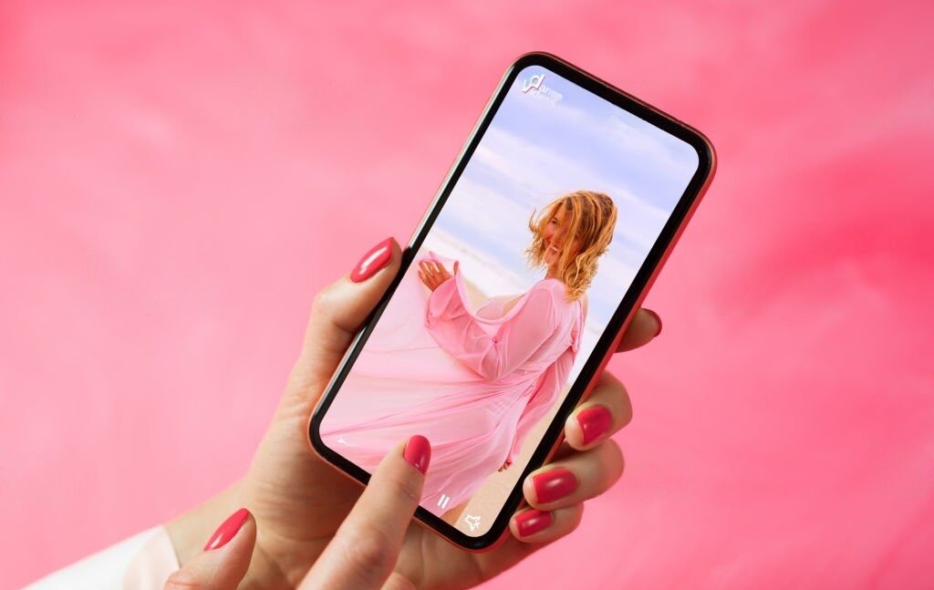 woman holding a phone with a video of tiktok content creator